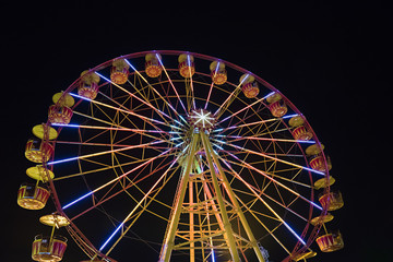 Ferris wheel with lights backlighting the night sky