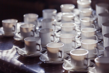 Closeup image of row of empty white tea cups with spoons