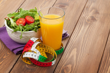 Healthy food and tape measure over wooden table