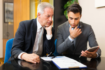 Two businessmen using tablet during a meeting