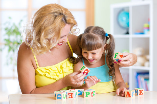 Mother and her kid playing with cubes and learning letters