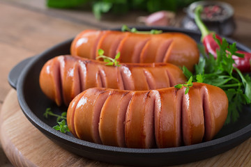 Sausages on the grill pan on the wooden background