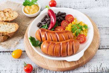 Sausages on the grill with vegetables on a platter. Top view