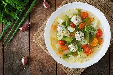 Diet vegetable soup with chicken meatballs and fresh herbs in bowl. Top view