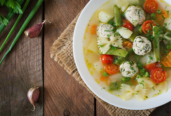 Diet vegetable soup with chicken meatballs and fresh herbs in bowl. Top view