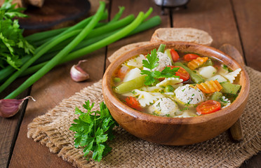 Diet vegetable soup with chicken meatballs and fresh herbs in wooden bowl