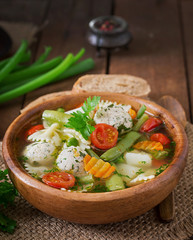 Diet vegetable soup with chicken meatballs and fresh herbs in wooden bowl