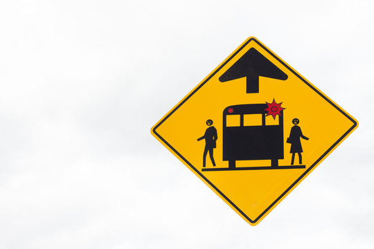 horizontal image of a yellow triangle warning sign of back of a bus with a flashing red light and two people getting off bus on white background.