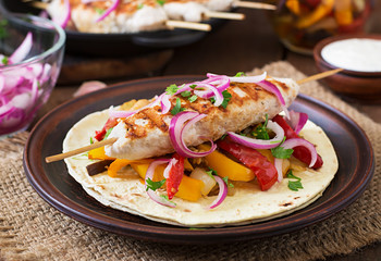 Chicken kebab with grilled vegetables and tortilla wrap.