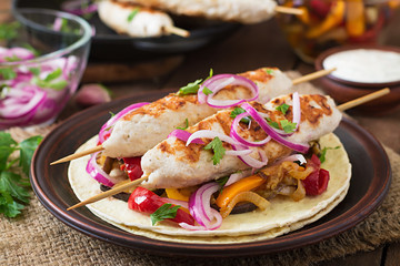 Chicken kebab with grilled vegetables and tortilla wrap.