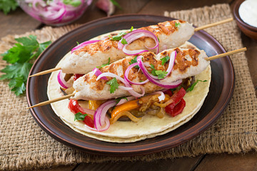 Chicken kebab with grilled vegetables and tortilla wrap.