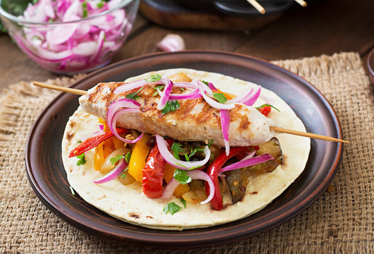 Chicken kebab with grilled vegetables and tortilla wrap.