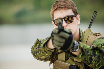 young soldier aiming and shooting with a pistol