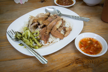 Stewed pork leg on rice with side bowl on wooden table.Thai food