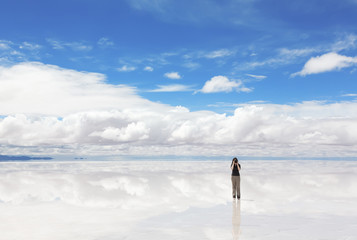 Woman taking photo of panorama lake Salar de Uyuni, Bolivia