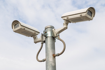 Two security cameras against blue sky