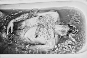 naked man lying in a bathtub