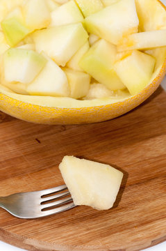 Melon on the fork with slices of melon in the bowl