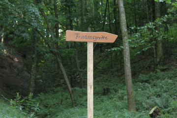 Holzschild mit Aufschrift Friedensgrotte im Wald