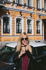 Fototapeta premium Girl with coffee on the background of cars and houses