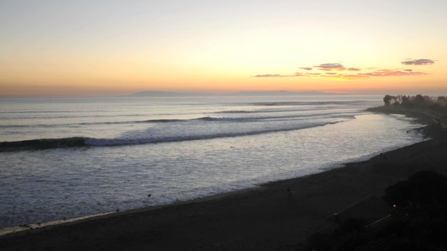 Wide time lapse of surfers and waves at Ventura Point at sunset in Ventura, California.