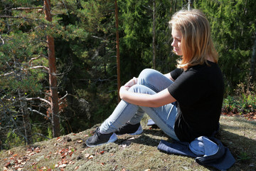 Naklejka na ściany i meble Blond Caucasian teenage girl sits in forest