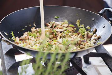 Mushrooms and leek simmering in wok.