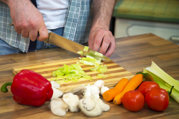 Unrecognizable man chopping fresh celery.