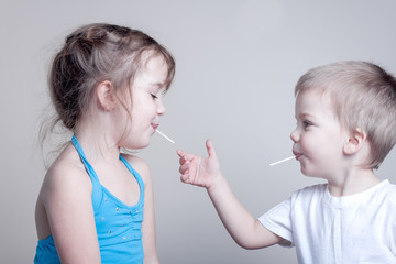 siblings having fun with lollypops - little brother is trying to