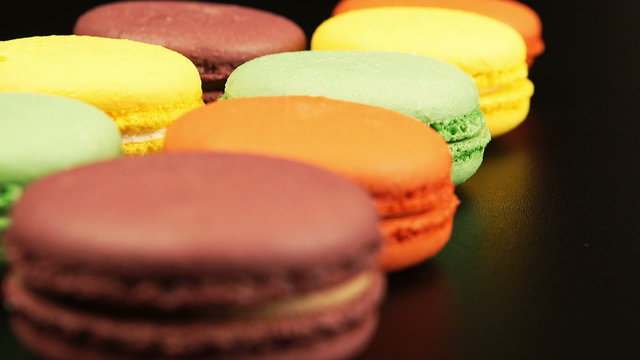 Changing of focus along the row of a macaroons on black table 
