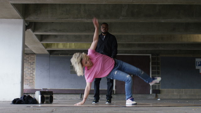 4K Female breakdancer dancing as her male friend watches on, in slow motion, shot on Red Epic Dragon