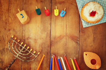 top view image of jewish holiday Hanukkah with menorah (traditional Candelabra), donuts and wooden dreidels (spinning top). retro filtered image
