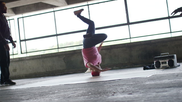 4K Female breakdancer finishes her dance moves in urban surroundings as friends cheer her on, in slow motion, shot on Red Epic Dragon