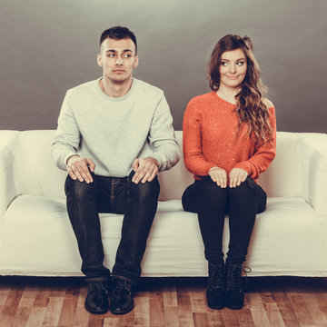 Shy woman and man sitting on sofa. First date.