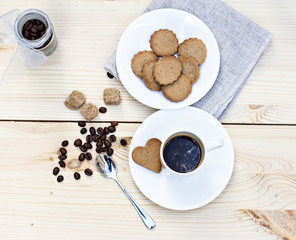 Ginger biscuits, cinnamon, a cup of hot coffee. Walnuts, hazelnuts on a wooden background
