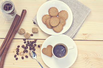 Ginger biscuits, cinnamon, a cup of hot coffee. Walnuts, hazelnuts on a wooden background. Tonned photo.
