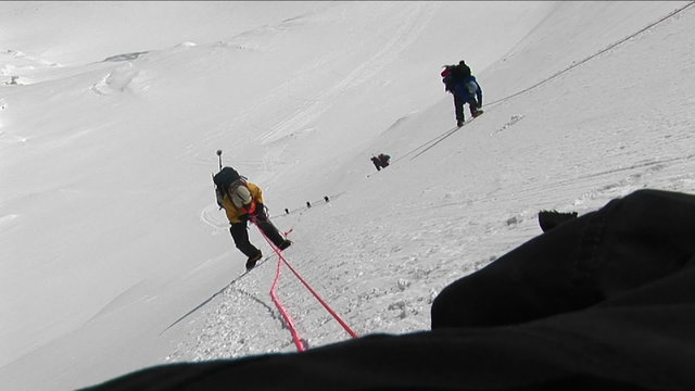 Climbers climbing down steep slope