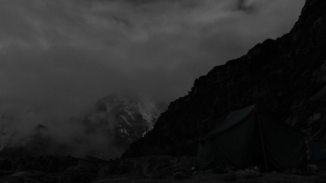Tent lite up at camp at night, climbers in and out
