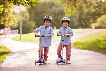 Two cute boys, compete in riding scooters, outdoor in the park, © Tomsickova