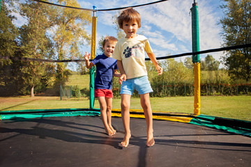 Two sweet kids, brothers, jumping on a trampoline, summertime, h