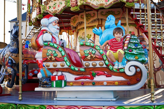 Sweet boy, riding in a Santa Claus sledge on a merry-go-round