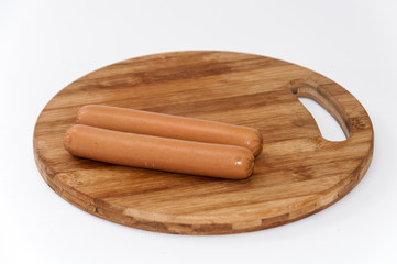 Two cooked hot dogs on the wooden board