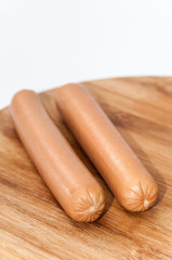 Two cooked hot dogs on the wooden board