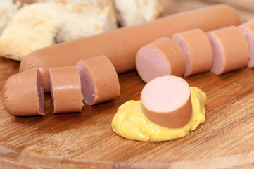 Sliced hot dog with mustard on the wooden board