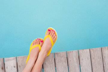 Woman with yellow flip flops by the pool - obrazy, fototapety, plakaty