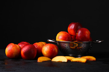 peaches in a metal plate on a black background