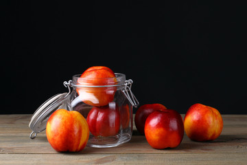 peaches in a jar on wooden table on black background