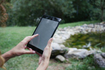 Close up to view young woman's hands hold tablet with empty screen