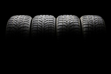 Set of four black car tires lined up horizontally