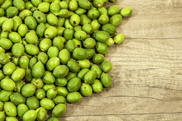 A lot green young walnuts in husks on wooden table
